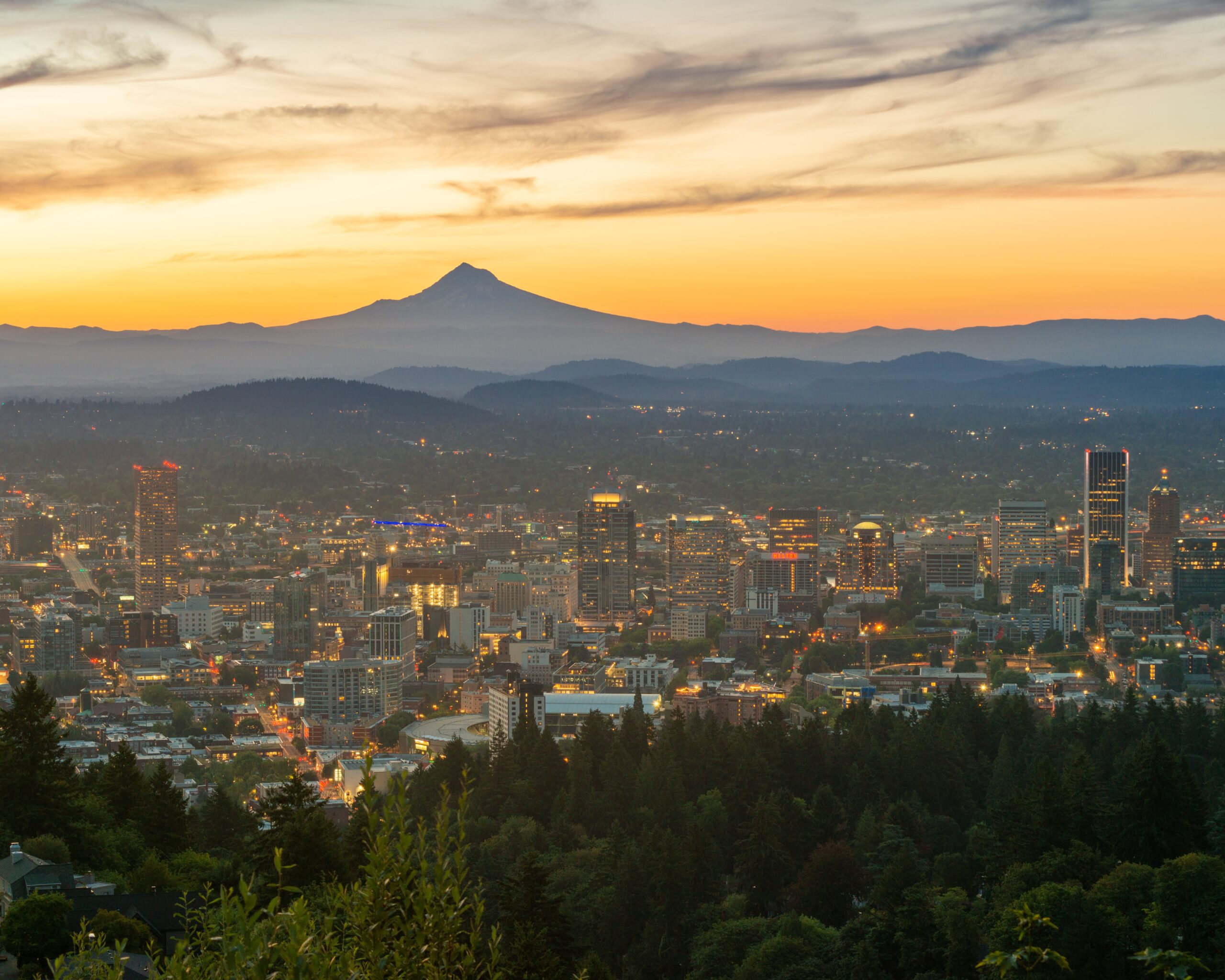 a city with mountains in the background at sunset