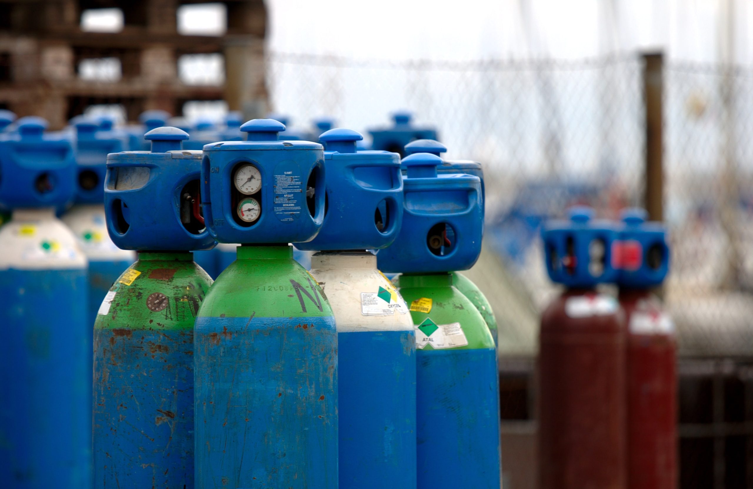 a bunch of blue and green gas cylinders are lined up
