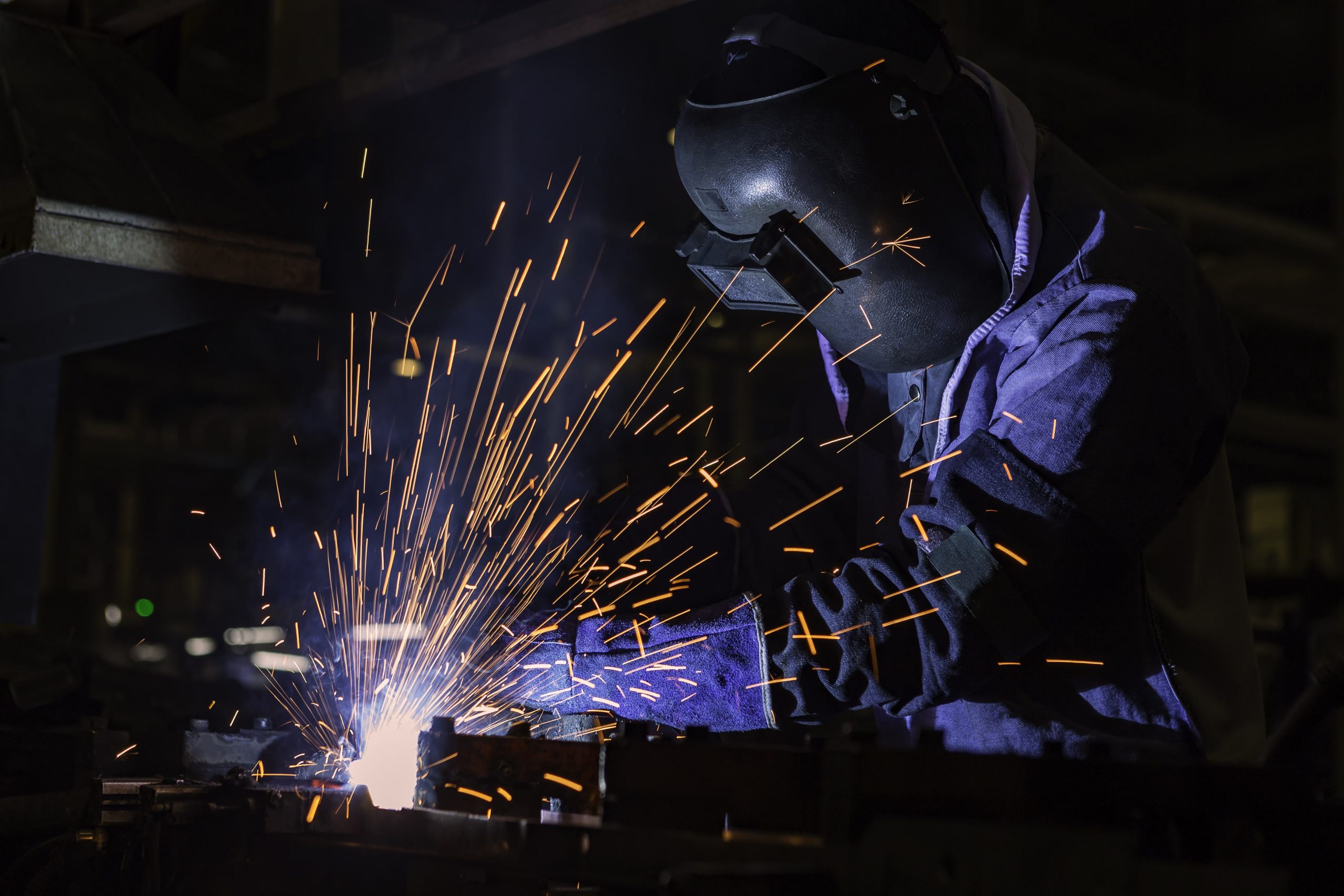 a man wearing a welding mask is welding a piece of metal