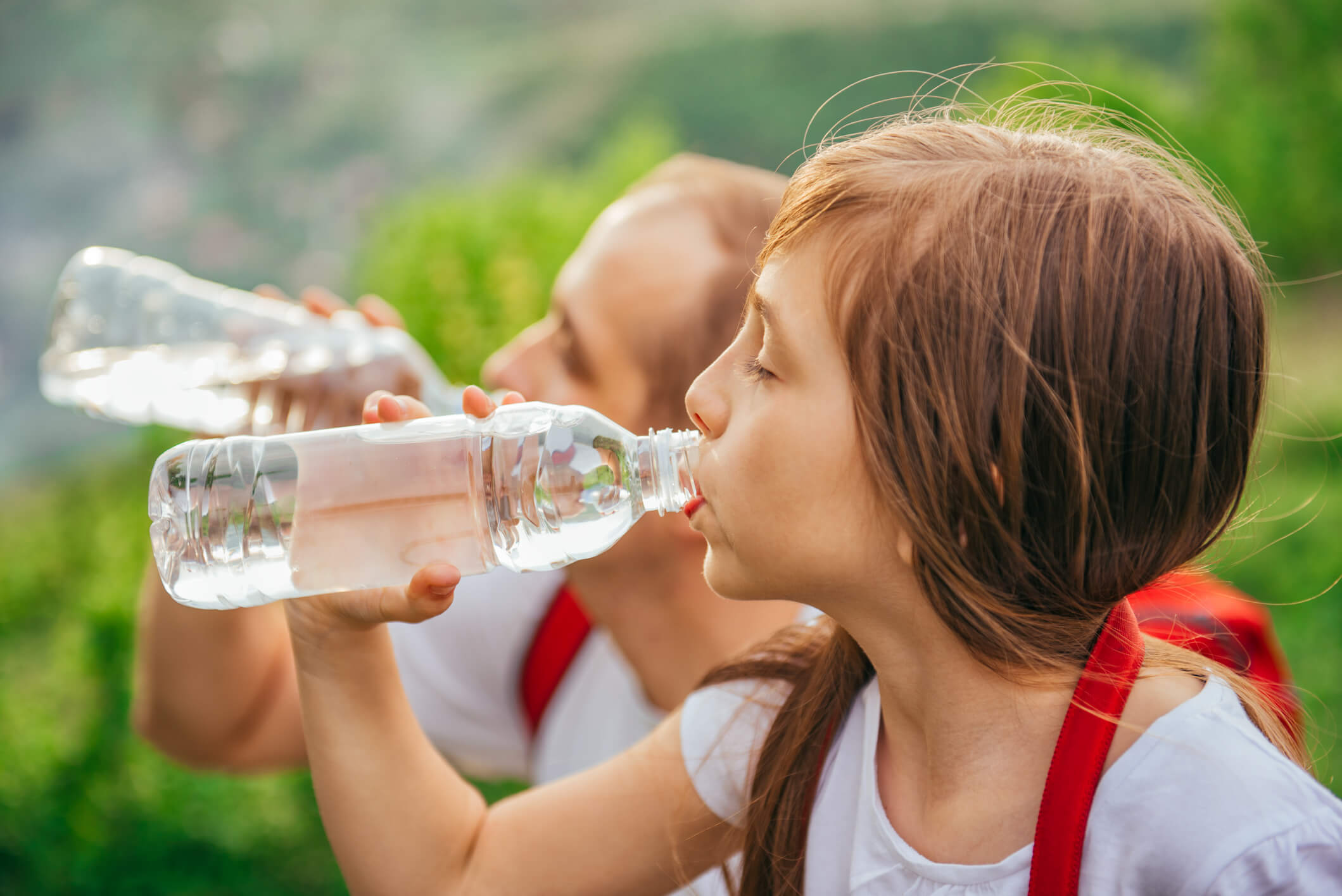a little girl drinking water from a plastic bottle