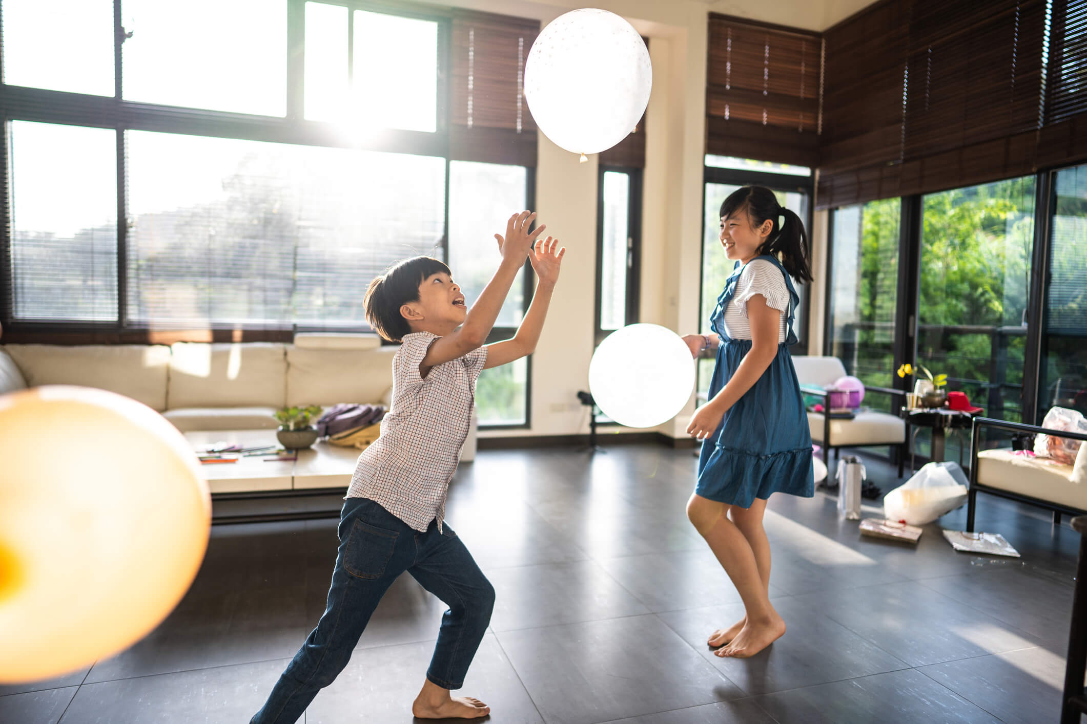 a boy and a girl are playing with balloons in a living room