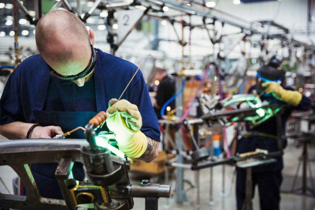 a man in a blue shirt is welding a piece of metal