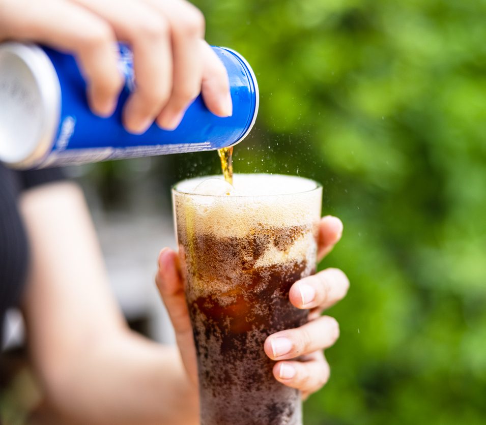 a can of soda is being poured into a glass