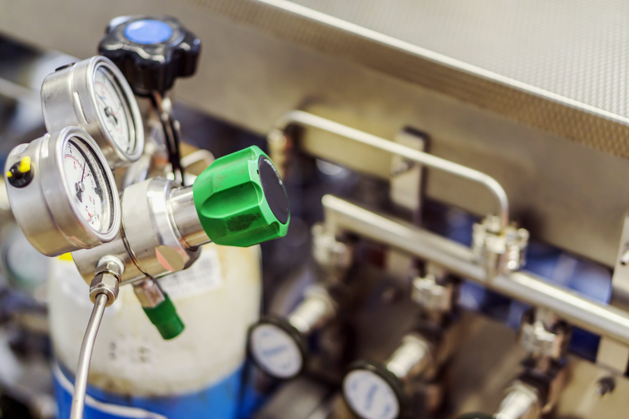 a valve with a green knob is connected to a cylinder