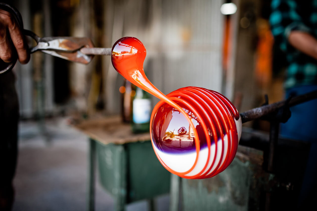 a person is blowing a red and white glass object