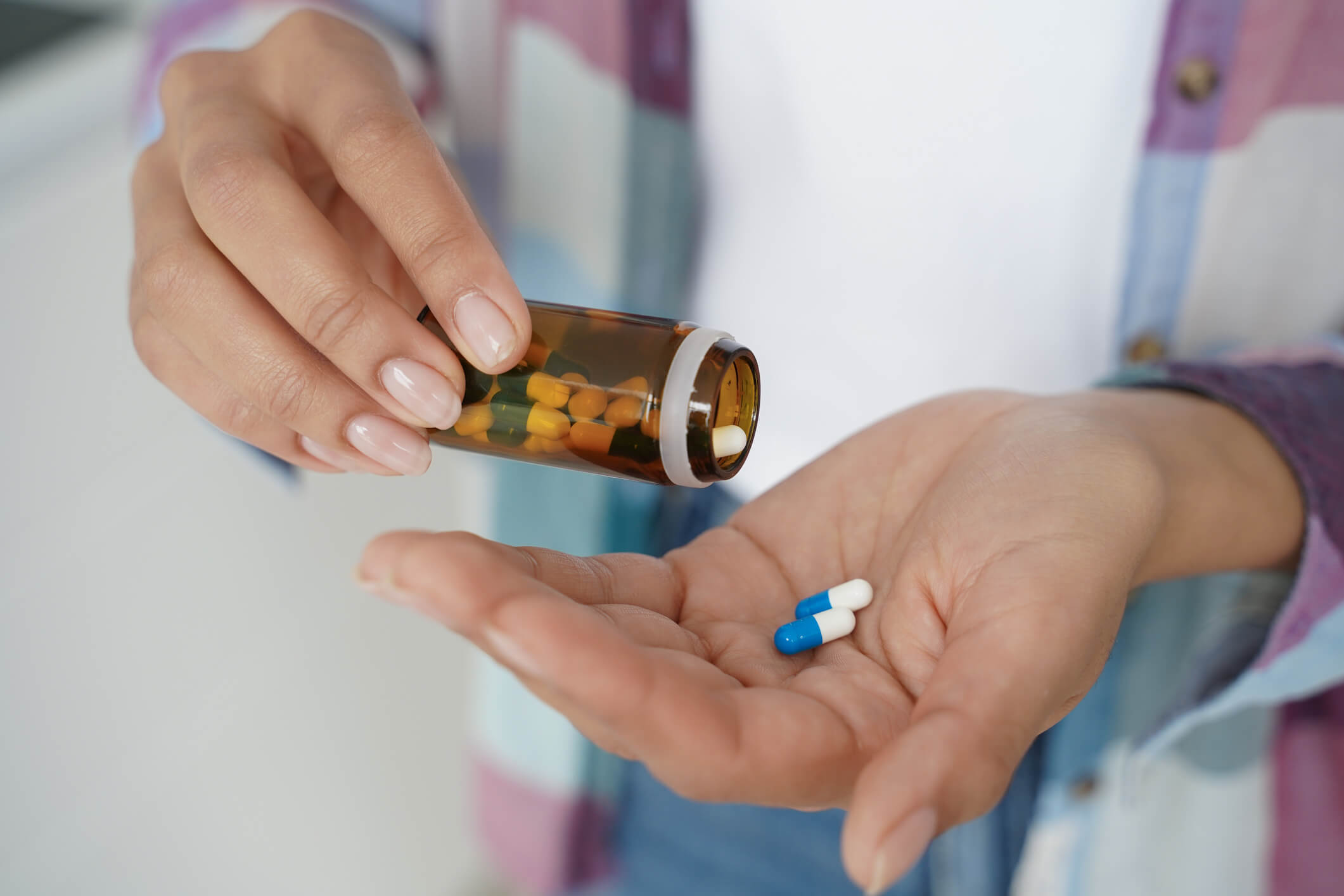 a woman is pouring pills from a bottle into her hand
