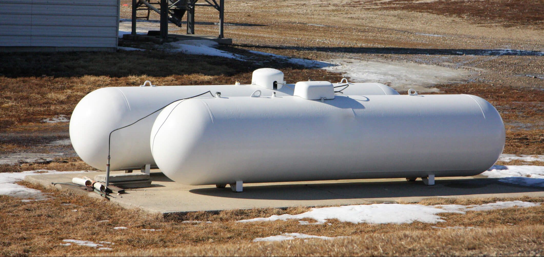two white propane tanks are sitting in a field