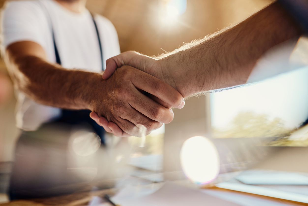a man shaking hands with another man in a white shirt