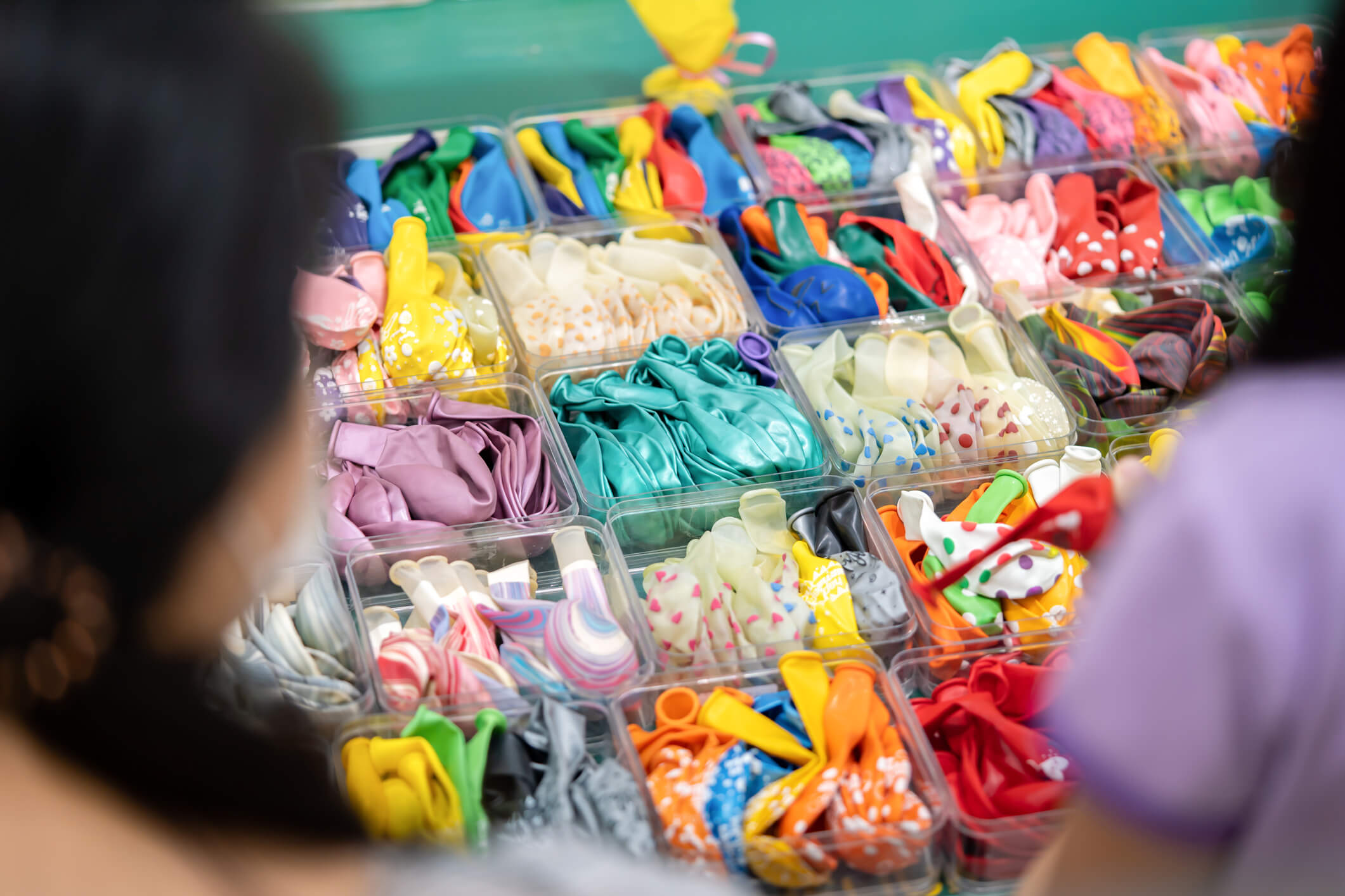 a bunch of balloons are displayed in plastic containers