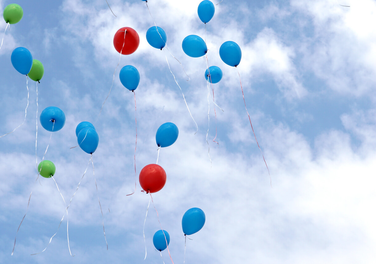 red blue and green balloons are flying in the sky