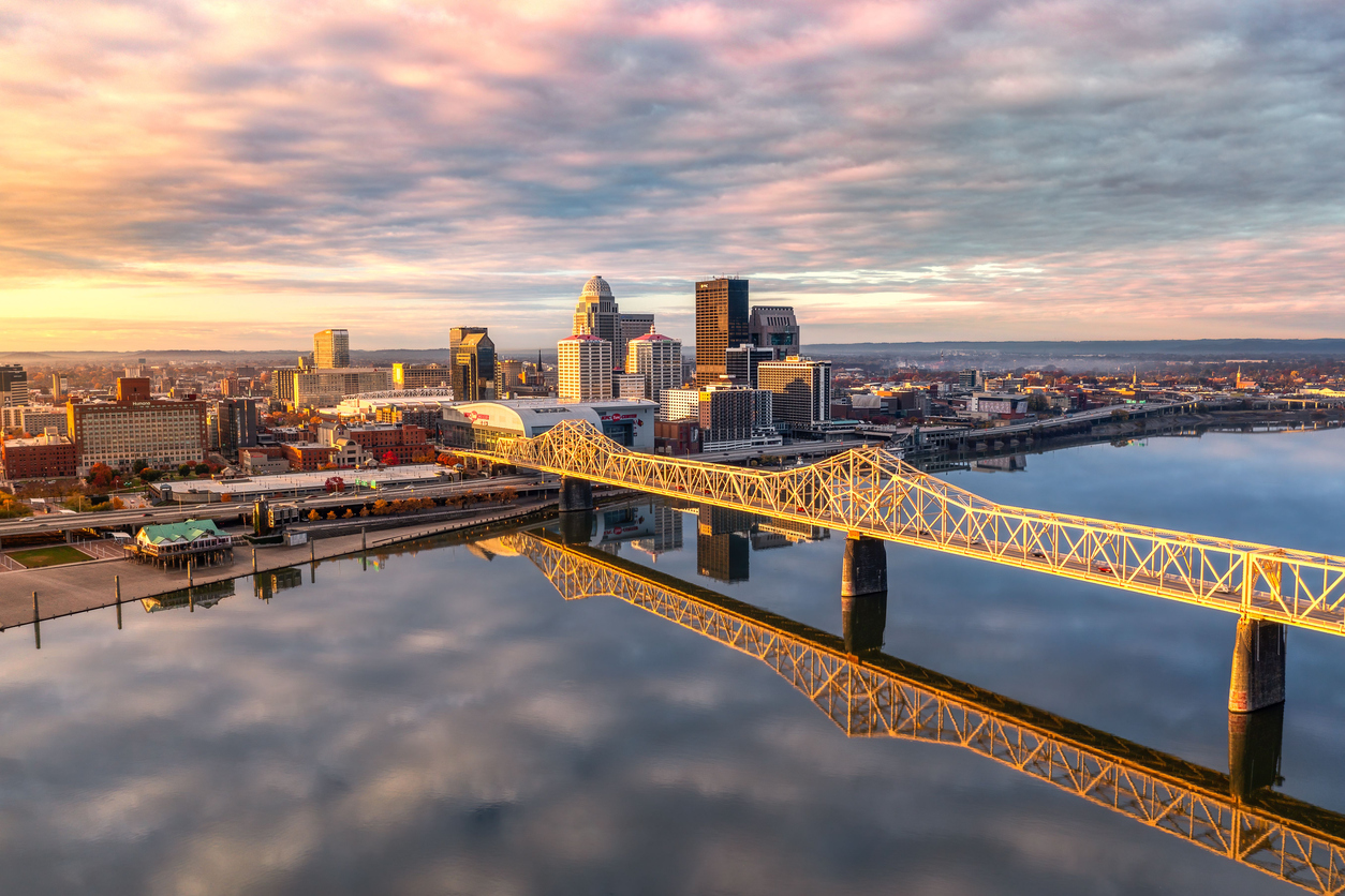 a bridge over a body of water with Louisville, KY in the background