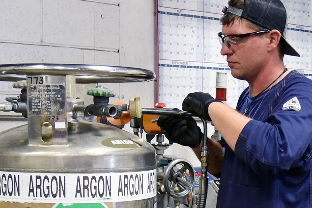 a man is working on a cylinder labeled argon argon argon