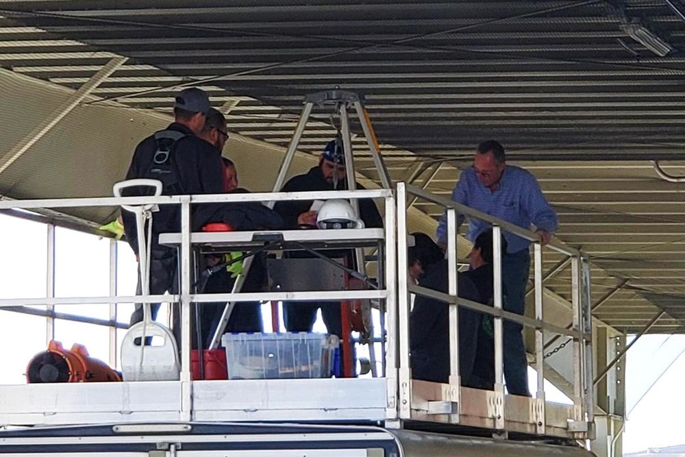 a group of men standing on a platform with one wearing a helmet with the letter d on it