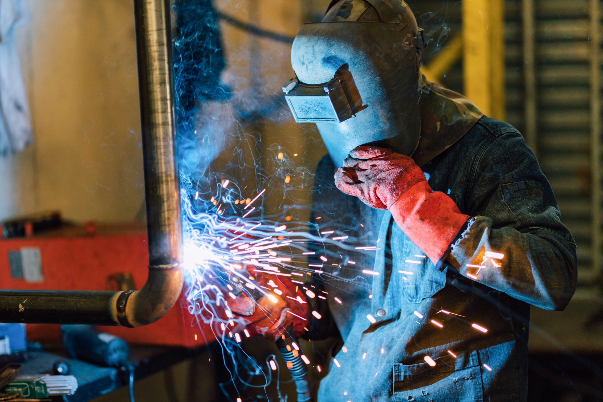 a man wearing a welding mask is welding a pipe