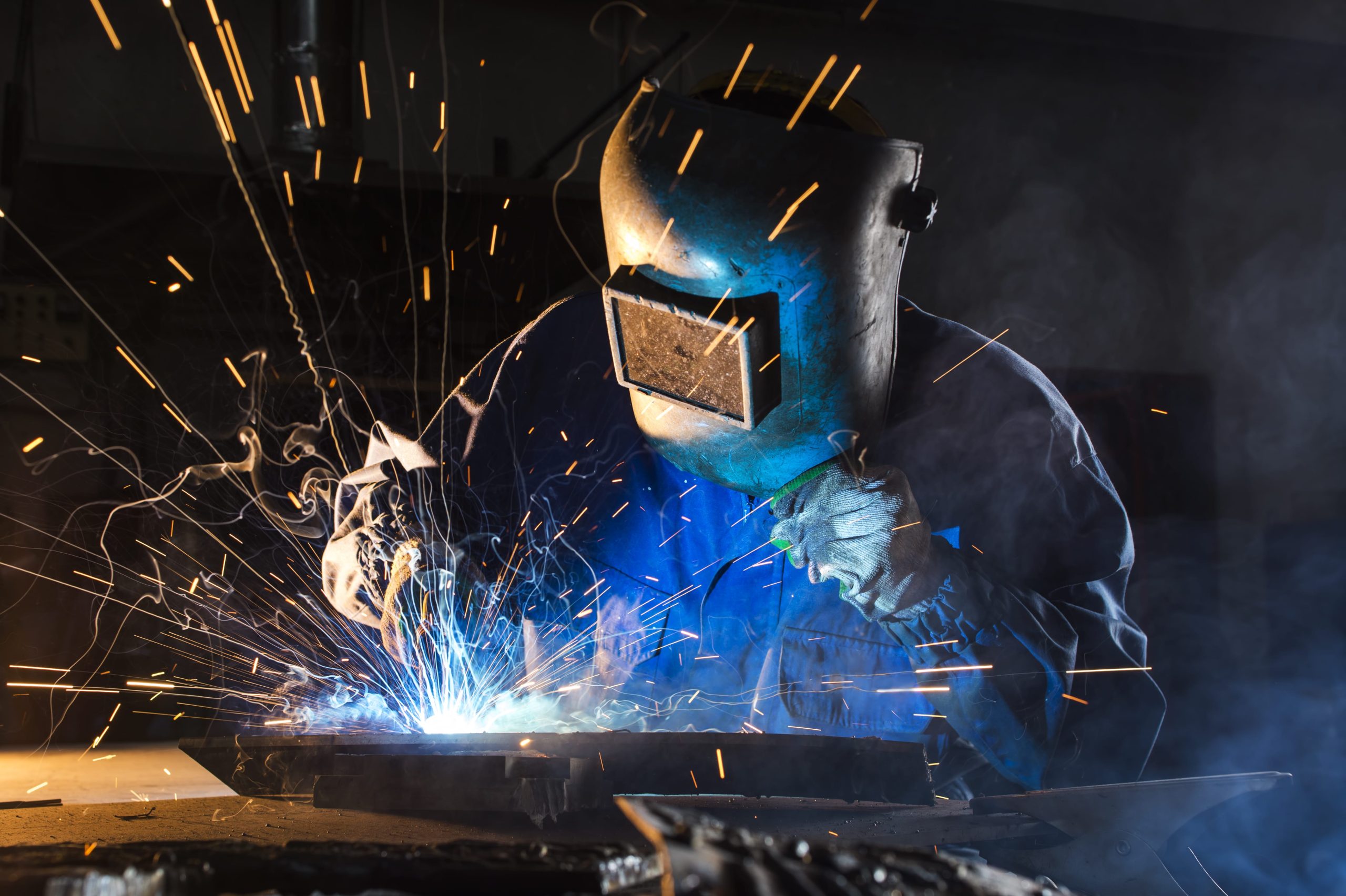 a man wearing a welding mask is welding a piece of metal