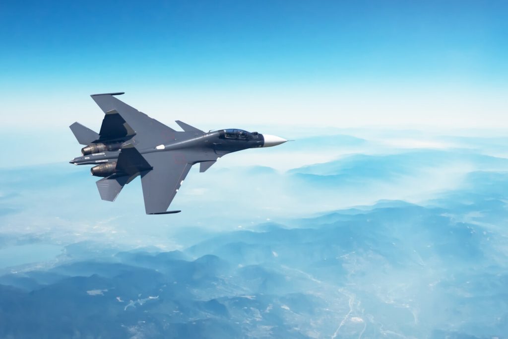 a fighter jet is flying in the sky with mountains in the background