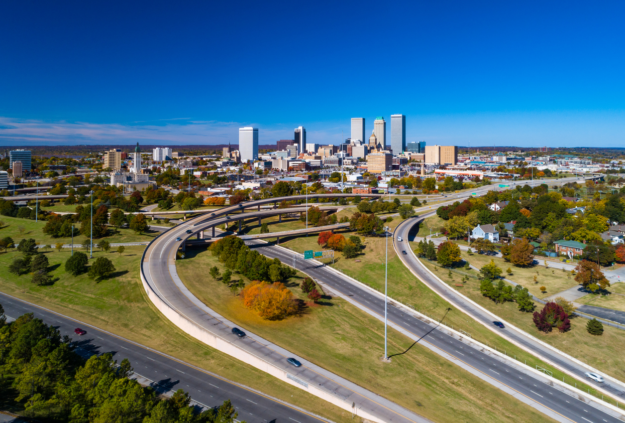 an aerial view of a highway intersection with a city skyline in the background