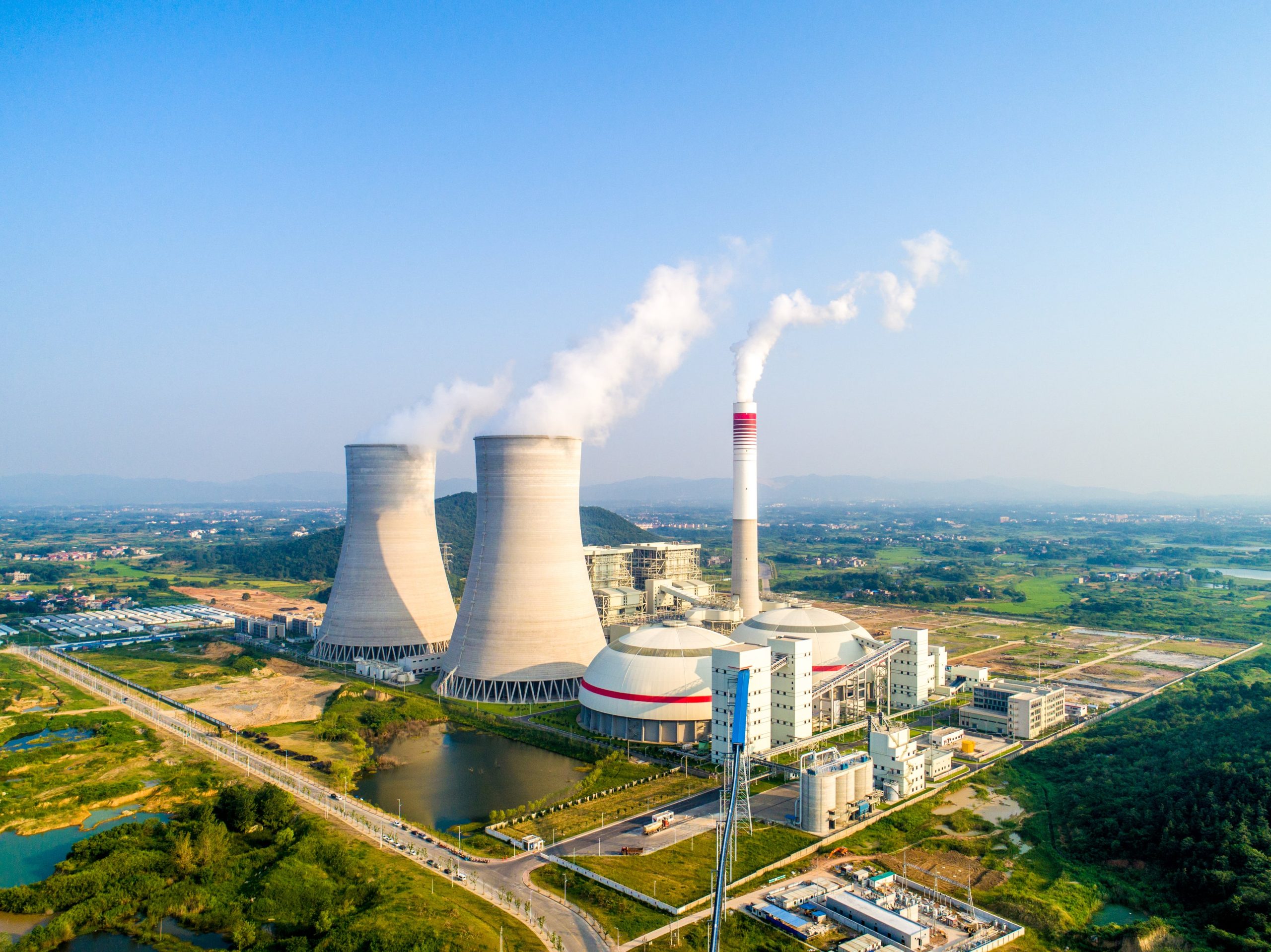 an aerial view of a nuclear power plant with smoke coming out of the cooling towers