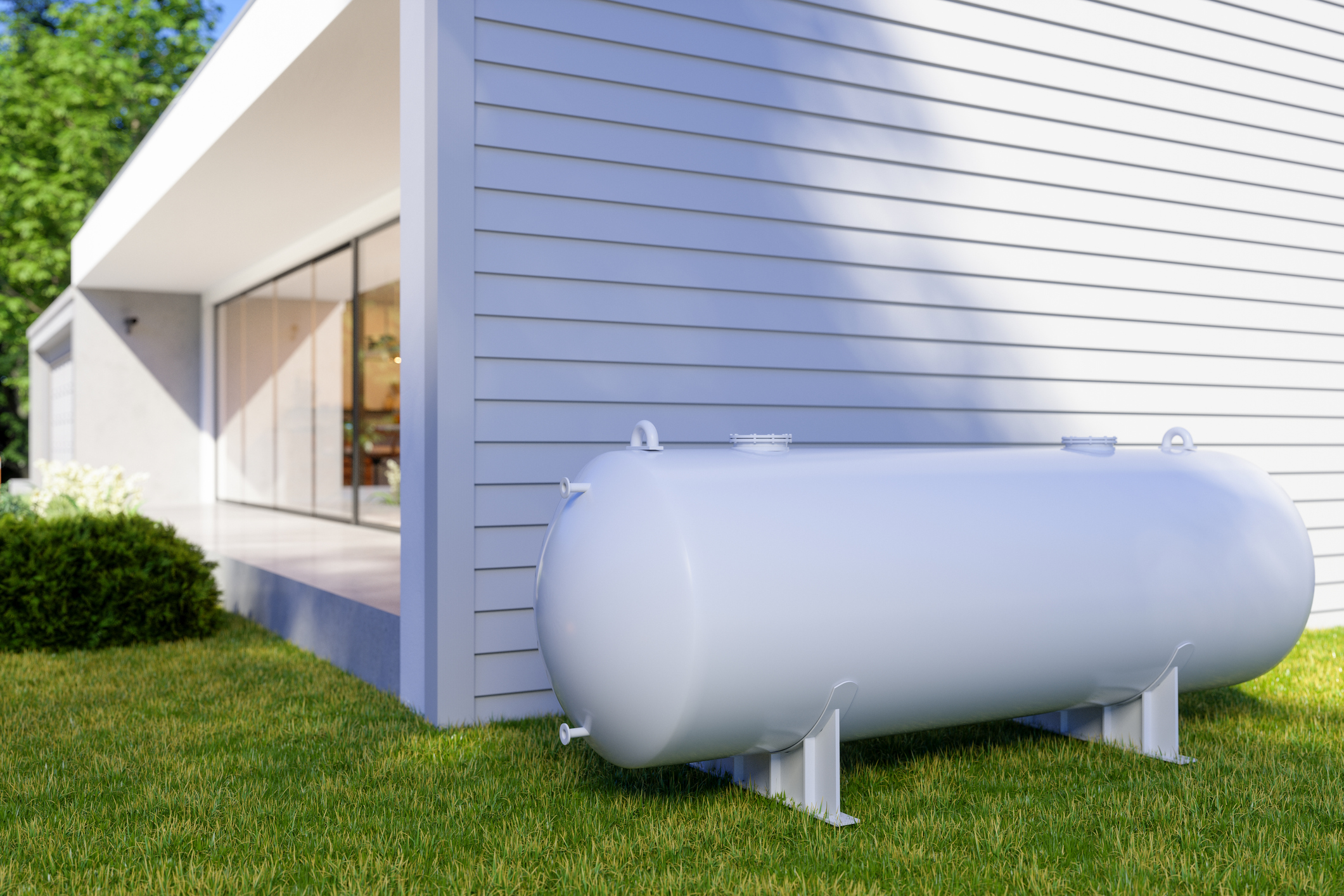 a large white propane tank sits in the grass in front of a house