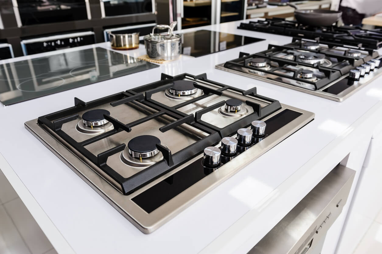 a stainless steel stove top with black knobs