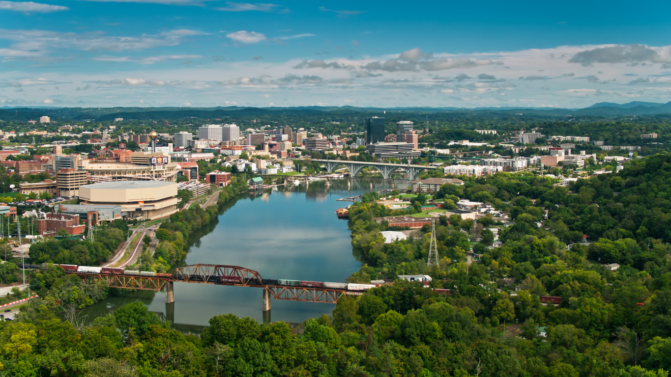 a bridge over a river with Knoxville, Tennessee in the background