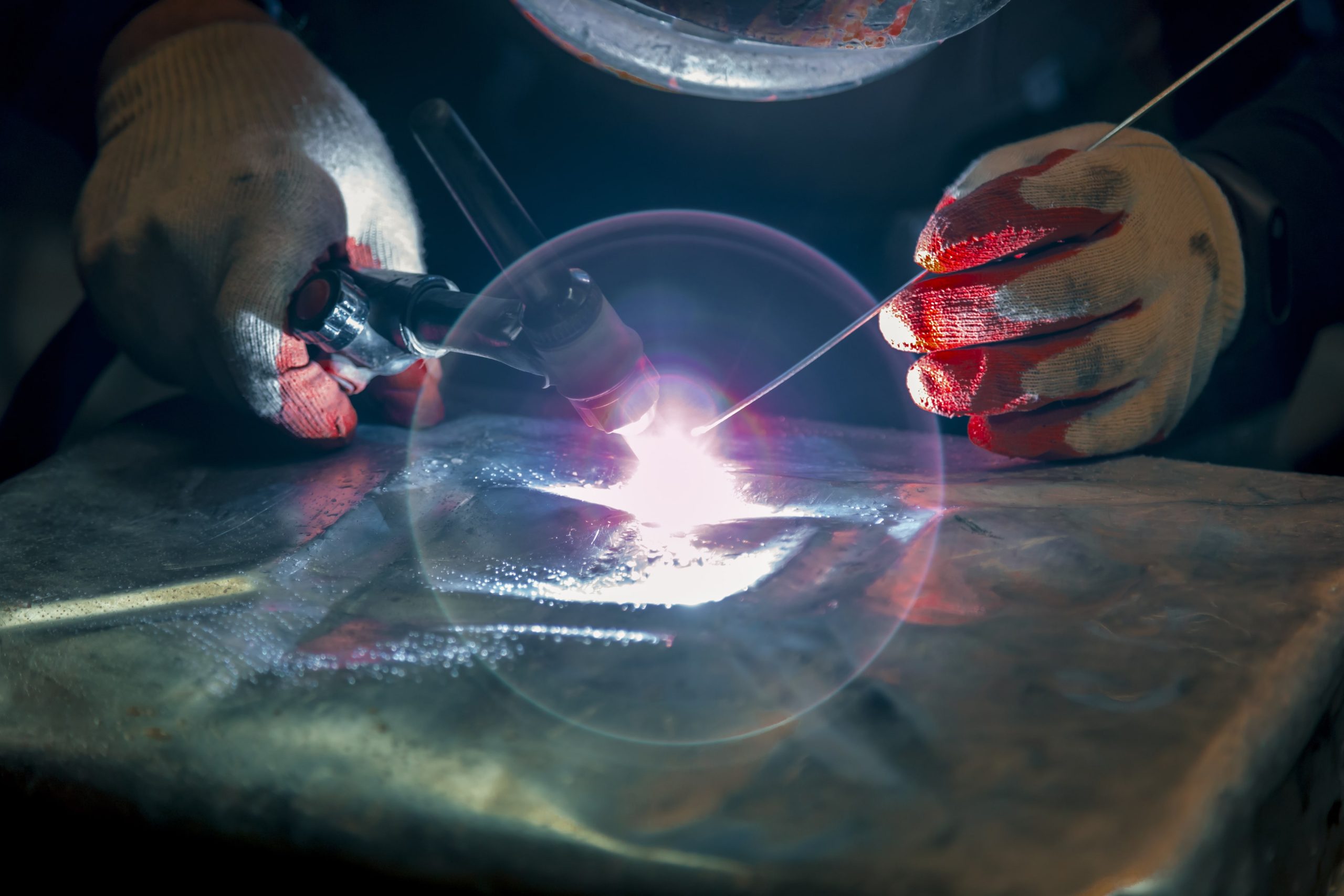 a person wearing red gloves is welding a piece of metal