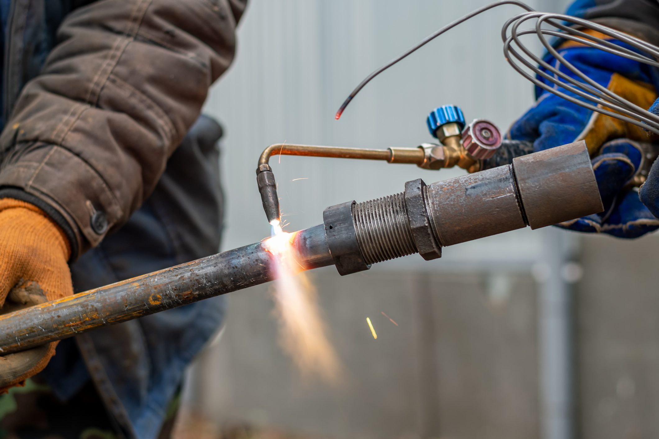 a man wearing gloves is welding a pipe with a torch