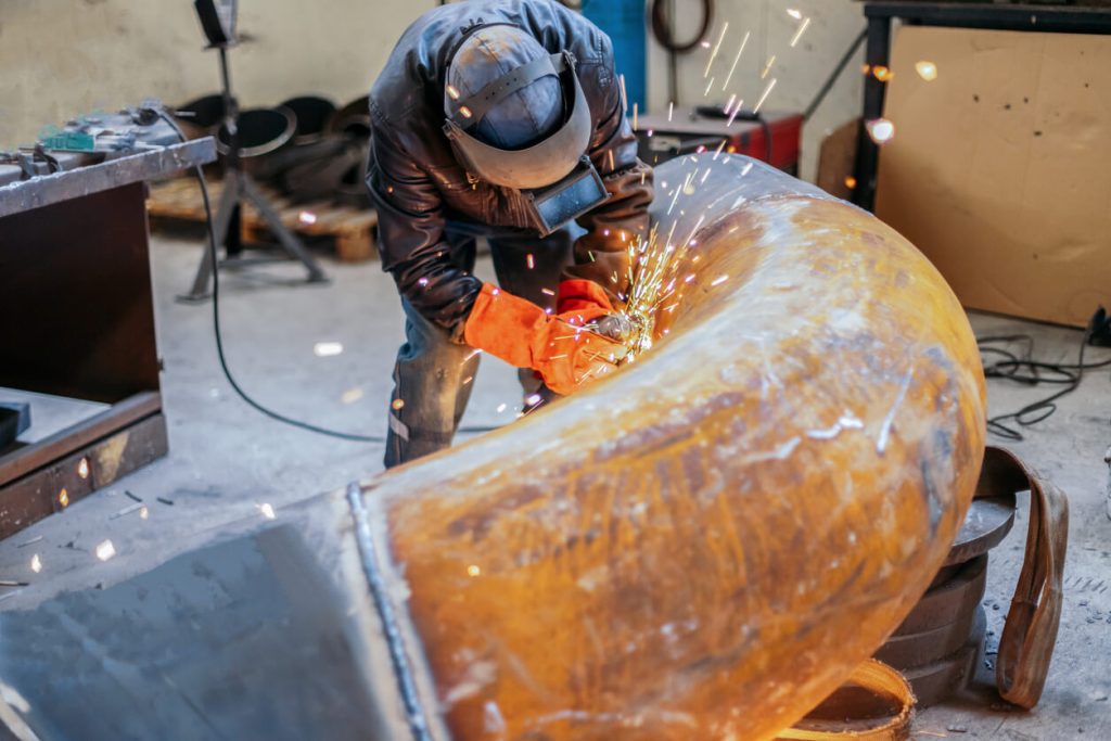 a man wearing a welding helmet is grinding a piece of metal
