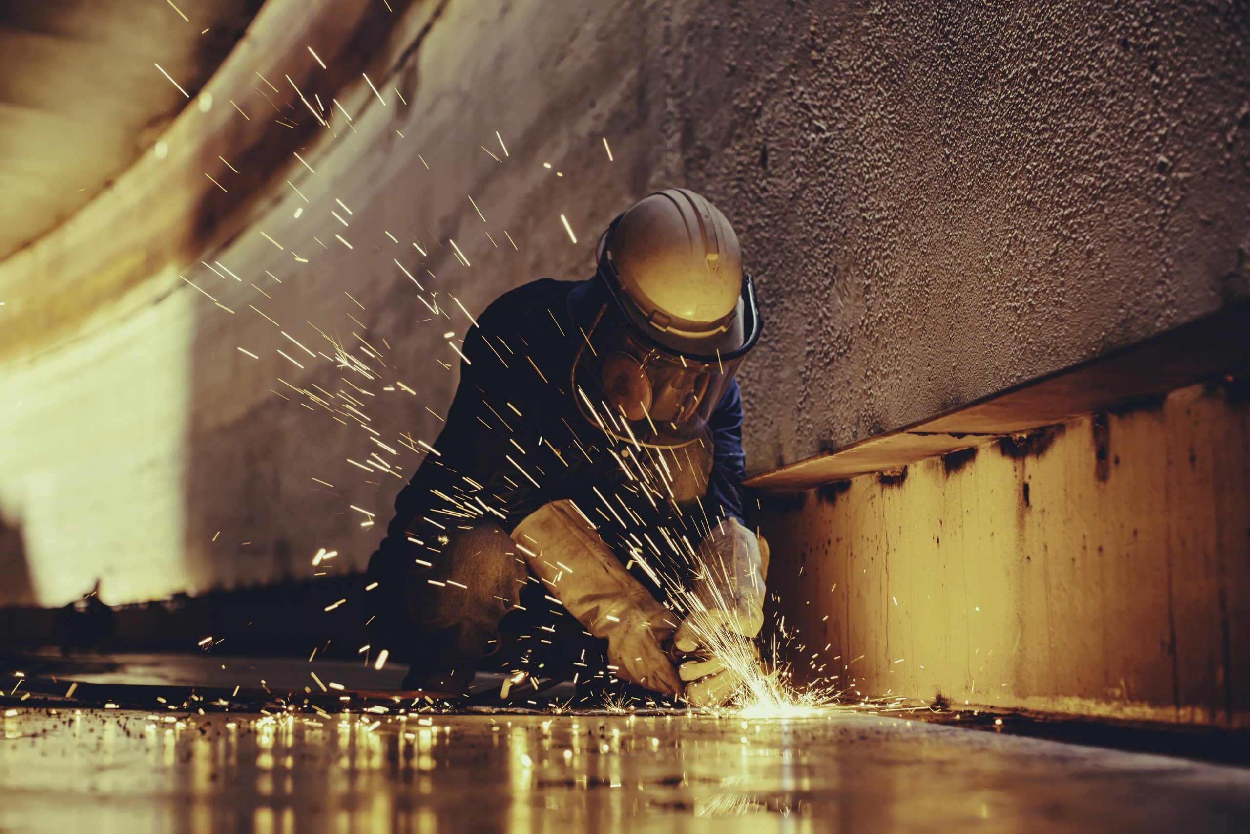 a man wearing a hard hat is welding a piece of metal