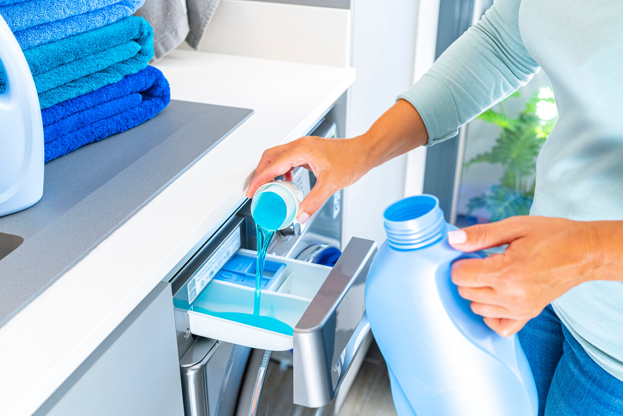 a woman pouring laundry detergent into a washing machine