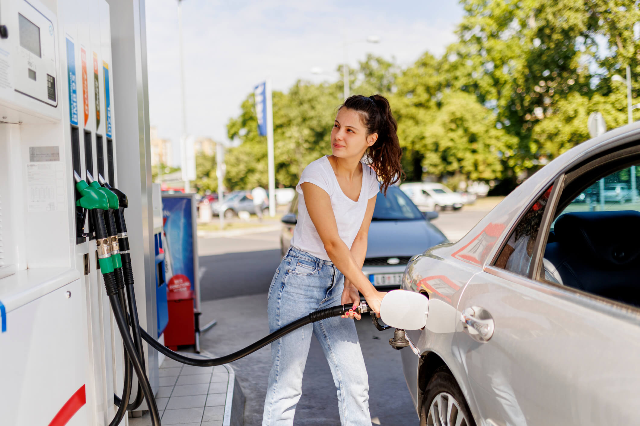 a woman is pumping gas into her car at a gas station