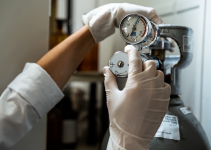 a person wearing white gloves is holding a gauge with the number 12 on it