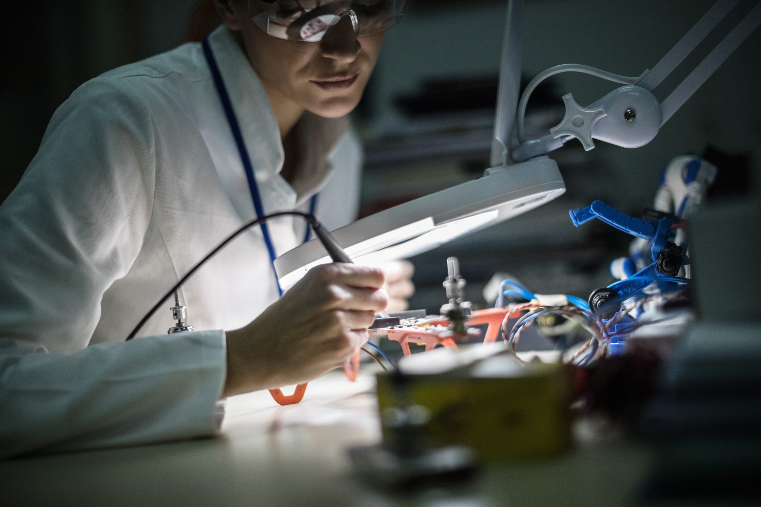 a woman in a lab coat is working on a device under a magnifying glass