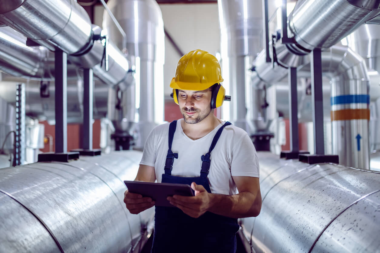 a man wearing a hard hat and headphones looks at a tablet