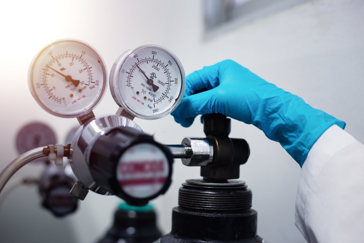 a person wearing blue gloves is adjusting a pressure gauge